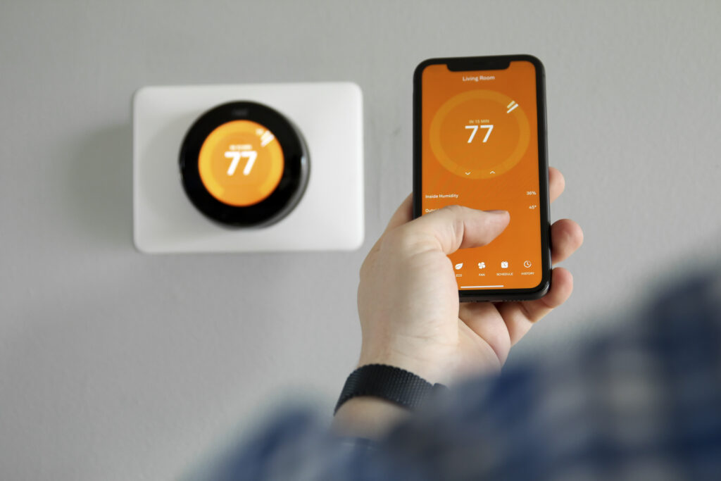 Man uses a mobile phone to adjust thermostat settings