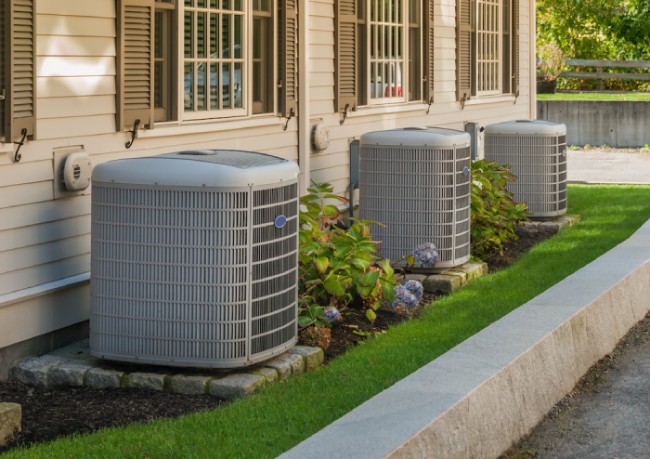 Three air conditioners positioned outside a house, highlighting the home's cooling system.